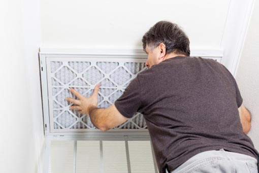 A man replaces the air filter in a wall-mounted unit.